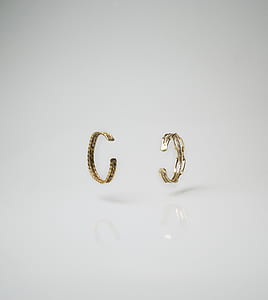 pair of gold-colored earrings on white surface thumbnail