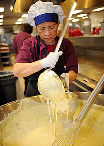 woman standing while holding ladle and bucket thumbnail