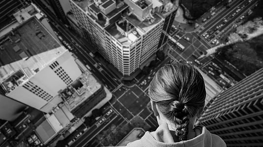 woman on top of building looking down in grayscale photo thumbnail