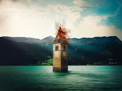 photo of a burning brown brick tower in the middle of sea during daytime thumbnail