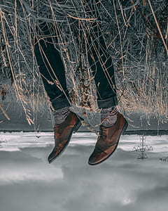 man wearing black pants and brown shoes fall on green grass near sea water photo during cloudy sky thumbnail