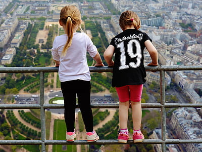 girl wearing black and white 19 jersey shirt beside girl wearing white shirt on gray metal rail at daytime thumbnail
