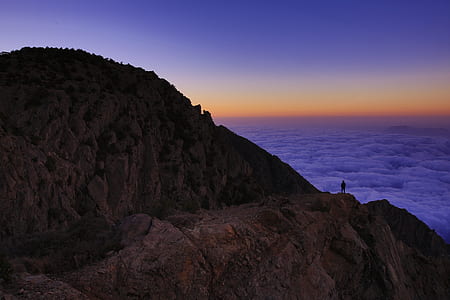 person on hill watching the clouds thumbnail