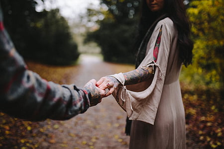 woman holding man's hand standing near green leafed tree thumbnail