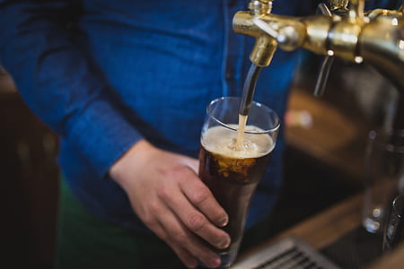 person holding drinking glass while filling liquid in it thumbnail