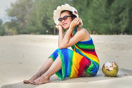 woman sitting on beach sand wearing brown sun hat thumbnail