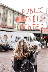 woman wearing black leather jacket and backpack holding white disposable cup thumbnail