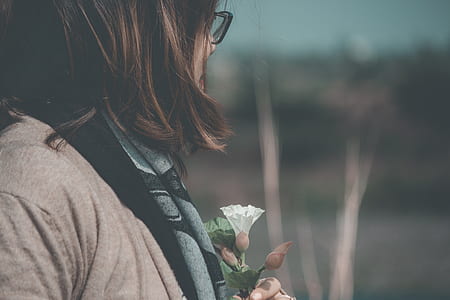 woman holding white petaled flower thumbnail