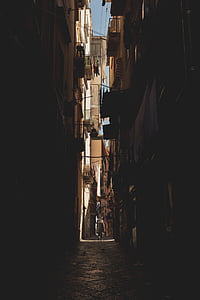 person walking on pathway between concrete buildings during daytime thumbnail