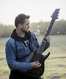 man playing guitar on grass field thumbnail