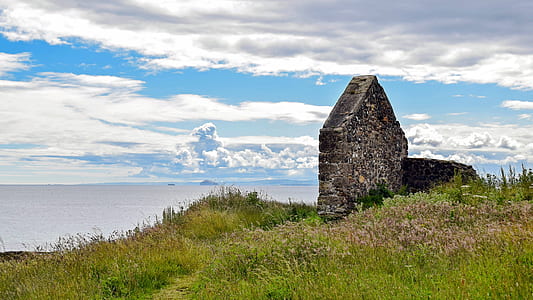 gray concrete structure on grass field under white sky thumbnail