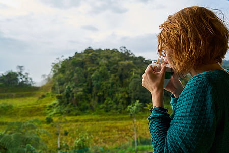 woman sipping drink from mug with trees in background thumbnail