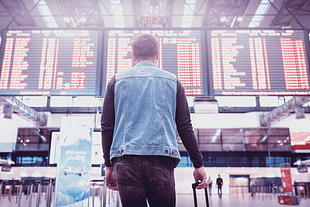 Young man with luggage checking flight timetable in international airport thumbnail