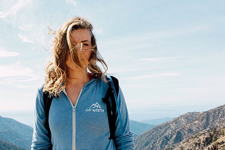 woman wearing blue Go North zip-up jacket standing on peak of a mountain during day thumbnail