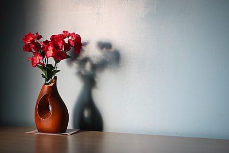 red flower in brown vase on table thumbnail