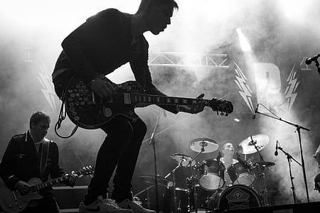 grayscale photo of man playing guitar in stage thumbnail