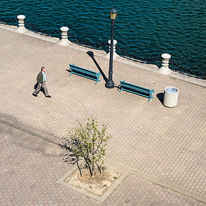 man walking near blue bench during daytime thumbnail