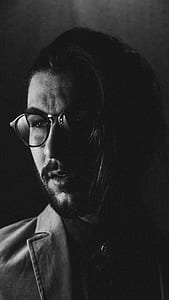man in coat and eyeglasses greyscale photography thumbnail