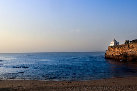 White Lighthouse Near Sea Under Blue Sky thumbnail