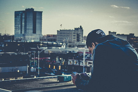 man wearing blue denim jacket looking at grey city thumbnail