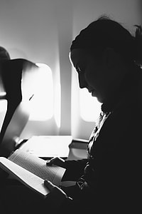 gray scale photography of woman reading inside plane thumbnail