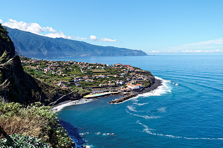 aerial photo of village near body of water beside mountain thumbnail