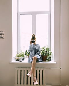 Woman in Grey Long-sleeved Dress Sitting on Window thumbnail
