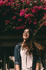woman in blue denim jacket near red bougainvilleas smiling thumbnail