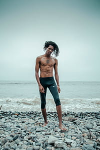 man wearing black Nike pants standing on seashore thumbnail