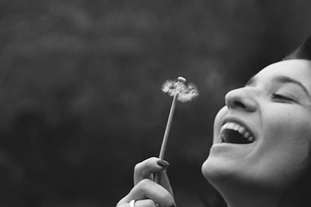 smiling woman holding dandelion flower thumbnail
