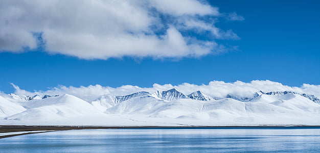 snow-covered mountain near body of water during daytime thumbnail
