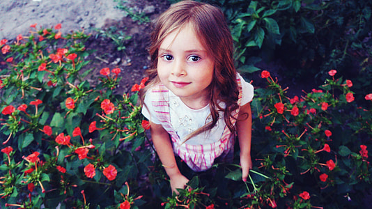 girl in white and red shirt near poppy flowers thumbnail