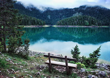 gray wooden bench facing the lake near mountain thumbnail