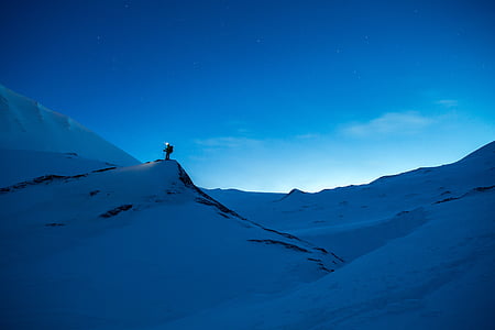 silhouette of man carrying backpack on snow filled mountain thumbnail