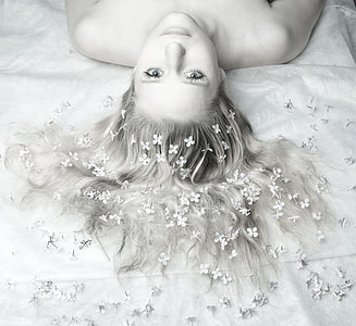 grayscale photography of woman lying down on white bed thumbnail
