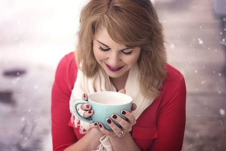 woman wearing pink shirt holding teal and white ceramic mug during winter thumbnail