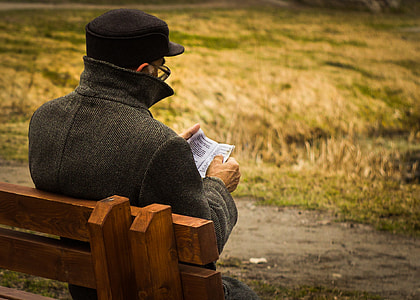 man sitting on bench while reading book thumbnail