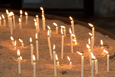 lighted white candle sticks on white sand thumbnail