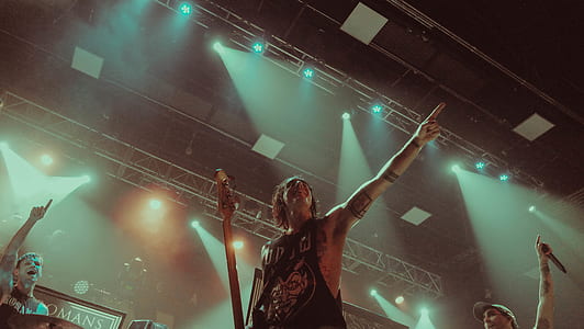 man wearing sleeveless top holding guitar pointing on crowd thumbnail