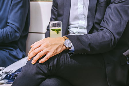man sitting on white bench holding clear drinking glass thumbnail