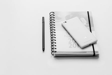 white Android smartphone on gray spiral book near black pen thumbnail