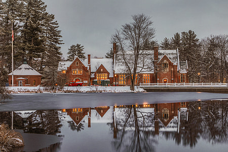 brown and white house near river under gray sky thumbnail
