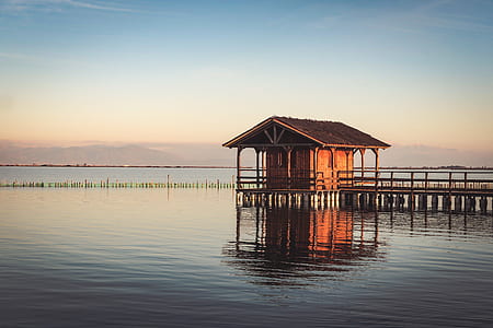 brown wooden house surrounded by ocean during daytime thumbnail
