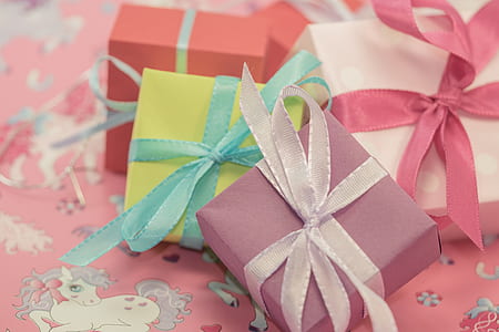four assorted-color gift boxes on white and pink pony print fabric sheet thumbnail