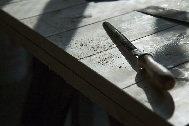 black metal hand tool on gray wooden table