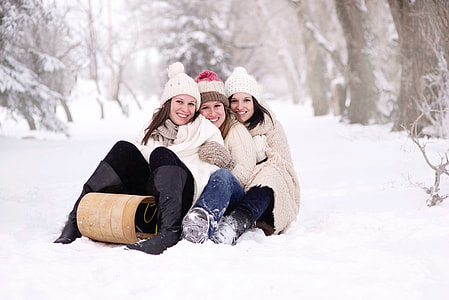 three women smiling and sitting on white snow thumbnail