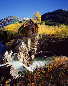 brown wooden house on top or rock formation surrounded by trees thumbnail