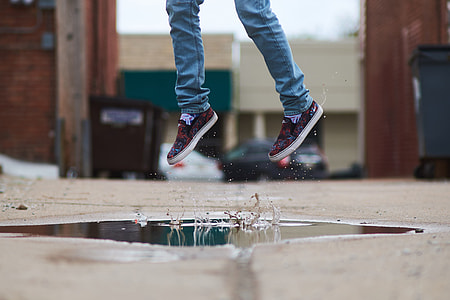 person in sneakers jumping on a water on the street thumbnail