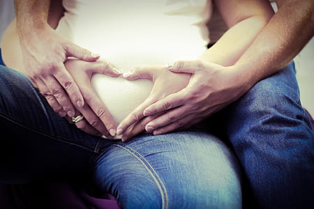 couple making heart shape hand gesture on woman belly thumbnail