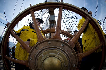 two men wearing yellow overalls near ship wheel at daytime thumbnail